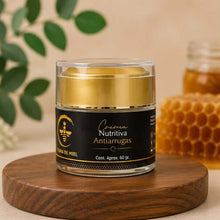 Cargar imagen en el visor de la galería, Crema Antiarrugas Con Colágeno en tarro sobre base de madera con fondo de miel y hojas verdes.