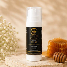 Cargar imagen en el visor de la galería, Protector solar FPS 50 miel y lavanda envase en mesa con miel natural y flores.