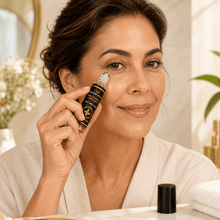 Cargar imagen en el visor de la galería, Mujer aplicando gel para ojeras con miel y ácido hialurónico en su rostro frente a un espejo.